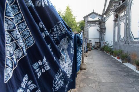 Zhoucheng Village in Dali, Yunnan - traditional Bai ethnic tie-dye workshops, whitewashed courtyard homes, and lively local markets against a backdrop of tea plantations.