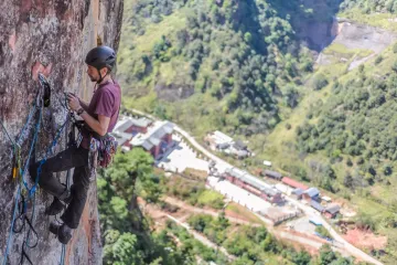 Adventure rock climber scaling a cliff face in Yunnan, China—ideal for outdoor sports and adrenaline tourism.