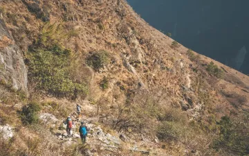 Hiker exploring the forested lower trails of Jade Dragon Snow Mountain, an epic outdoor adventure in Lijiang, China.